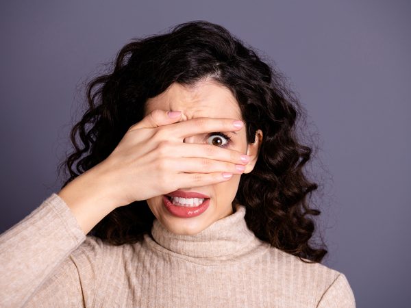 Close-up portrait of her she nice attractive pretty charming cute nervous, terrified girlish wavy-haired lady prying hiding behind palm fingers isolated over gray violet purple pastel background