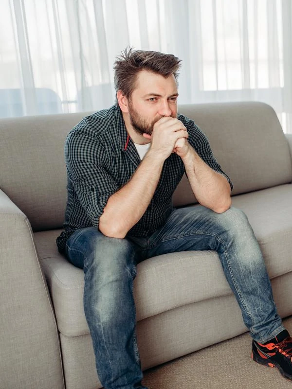 Sad male patient at psychologist, professional psychology support. Female doctor writes notes in notepad, man sitting on sofa