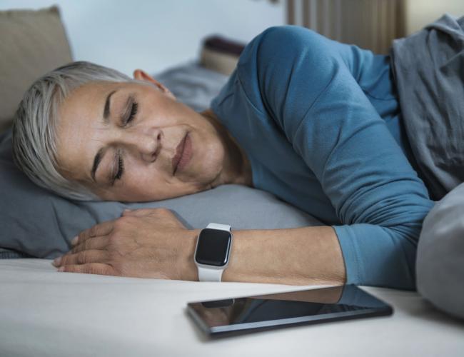 Sleep Apps - Tech-savvy Senior Woman Sleeping in Bed, Using Smart Phone and Smart Watch to Improve her Sleeping Habits