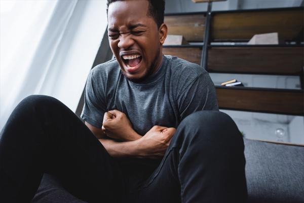 stressed african american man screaming while having panic attack at home